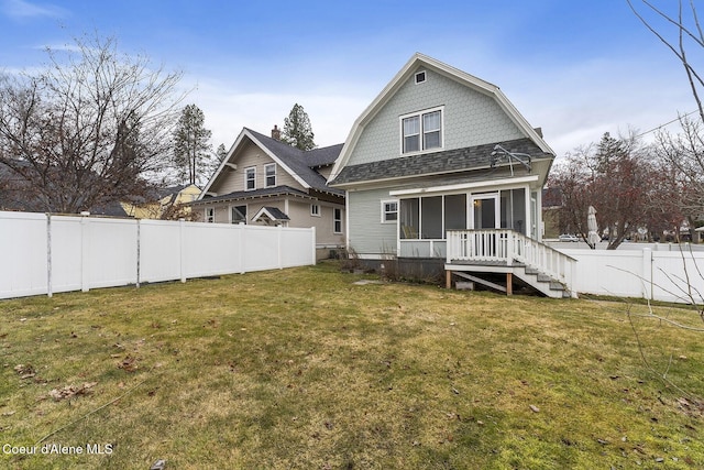 rear view of house with a yard, a shingled roof, a gambrel roof, a sunroom, and a fenced backyard