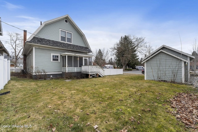 back of property with a gambrel roof, a lawn, fence, and a sunroom