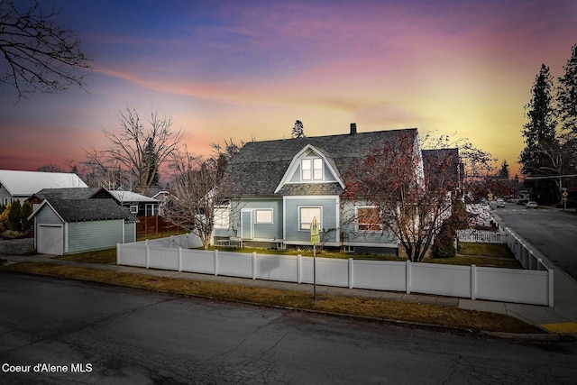 view of front of property featuring a fenced front yard, roof with shingles, a gambrel roof, and an outbuilding