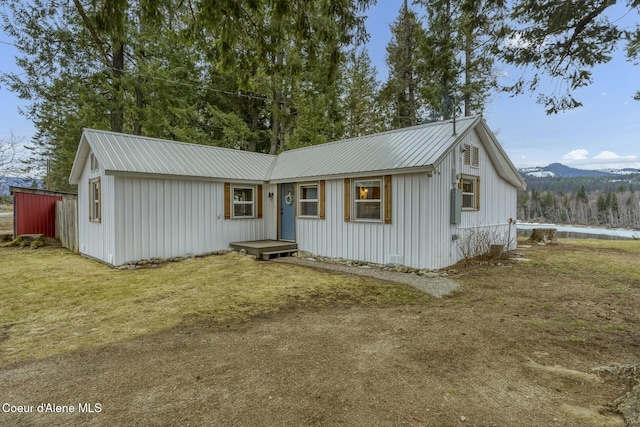 view of front facade with metal roof, board and batten siding, and a front lawn