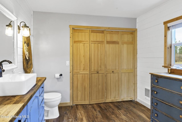 bathroom with visible vents, toilet, wood finished floors, baseboards, and vanity