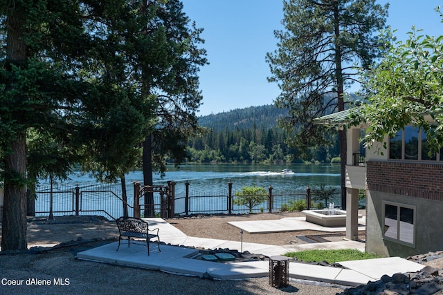 exterior space with a water view, fence, and a wooded view