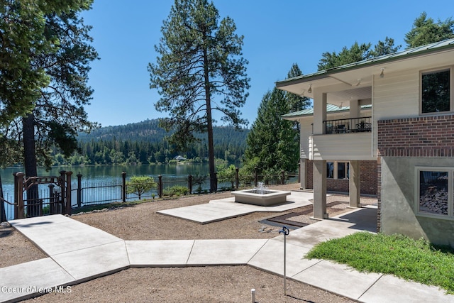 exterior space featuring a water view, fence, and a view of trees