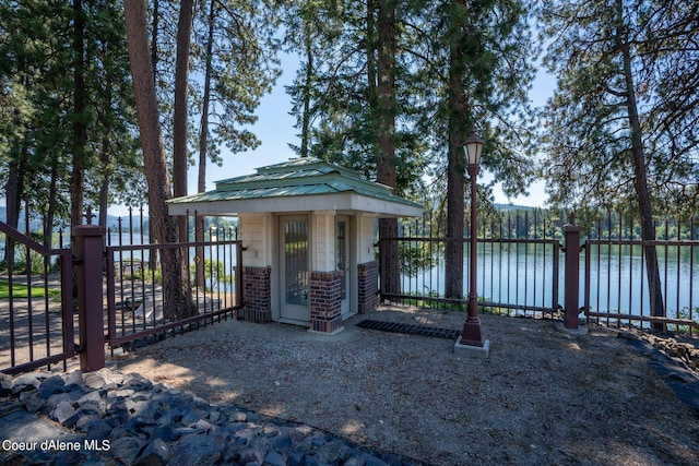 exterior space with metal roof, brick siding, a water view, and fence