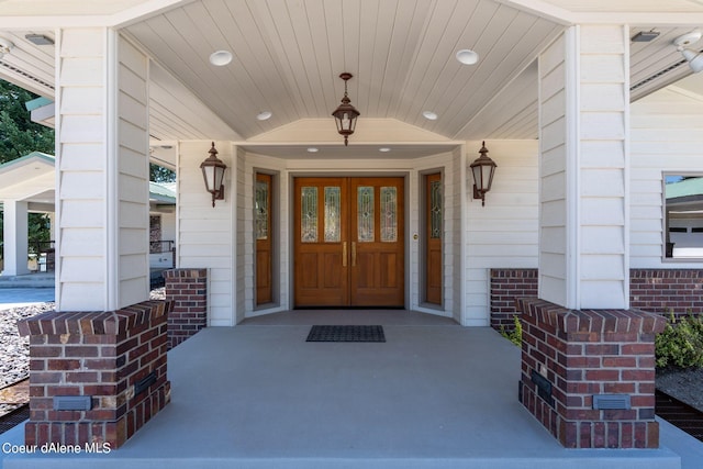 entrance to property with a porch and brick siding