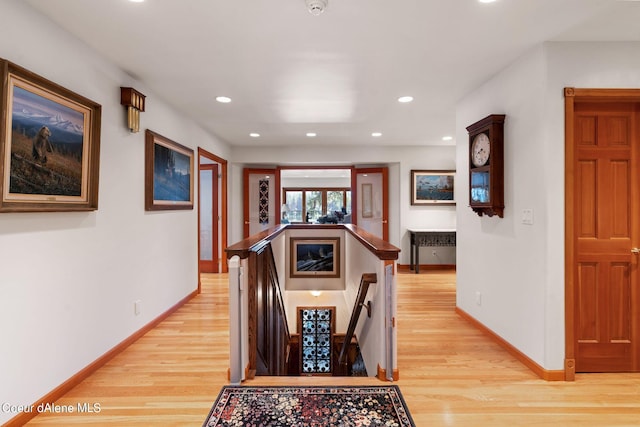 hall featuring recessed lighting, light wood-style flooring, baseboards, and an upstairs landing