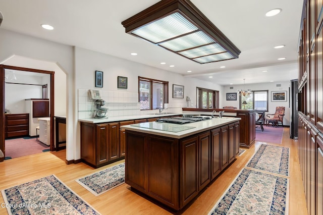 kitchen with recessed lighting, light countertops, a kitchen island with sink, dark brown cabinets, and light wood-type flooring