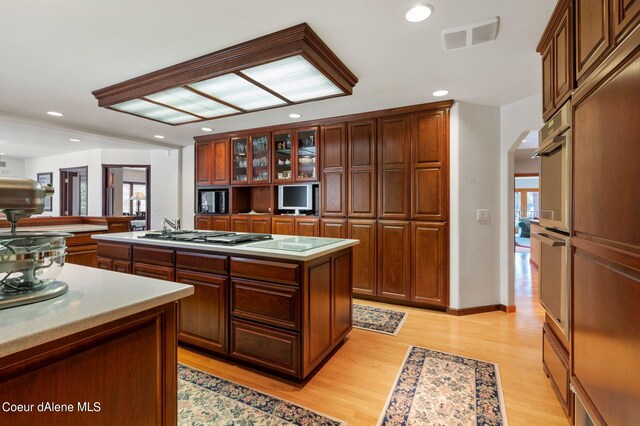 kitchen featuring arched walkways, light wood finished floors, recessed lighting, visible vents, and a kitchen island