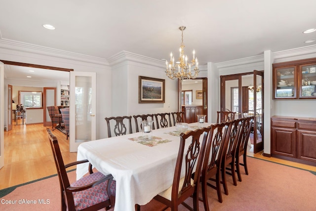 dining space with a notable chandelier, light wood-type flooring, a wealth of natural light, and crown molding