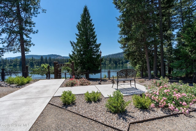 surrounding community with a forest view, a gate, fence, and a mountain view