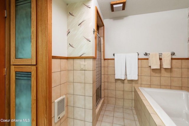 bathroom featuring tile walls, tile patterned flooring, a garden tub, and a shower stall