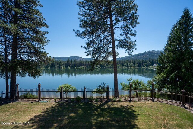 water view with a mountain view, a view of trees, and fence