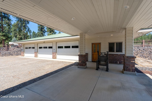 garage featuring driveway, fence, and a porch