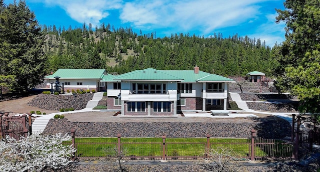 rear view of property featuring a forest view, fence private yard, a chimney, and stairs