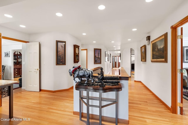 kitchen with a breakfast bar, light wood finished floors, arched walkways, recessed lighting, and baseboards