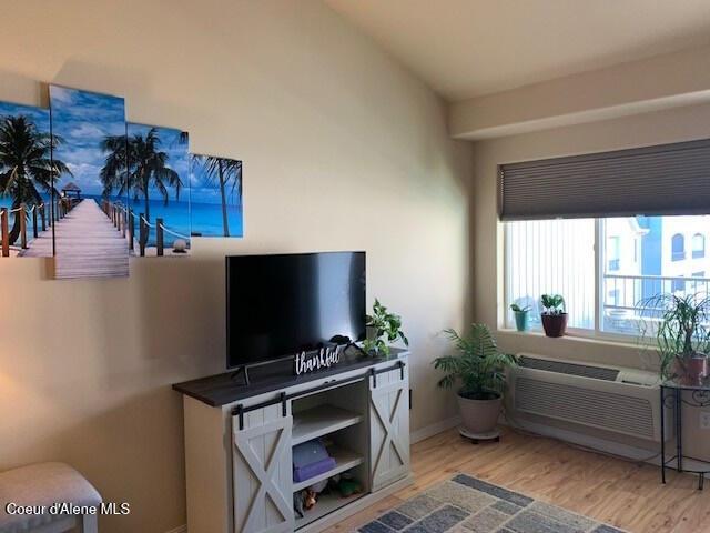 living room featuring lofted ceiling, baseboards, and wood finished floors