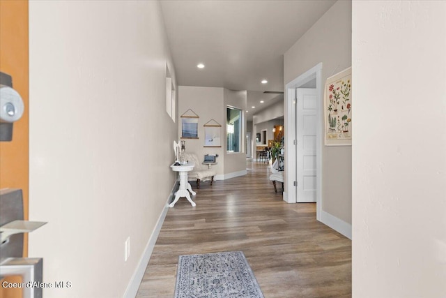 hallway featuring baseboards, wood finished floors, and recessed lighting