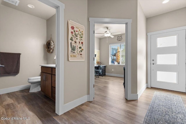 bathroom with visible vents, toilet, vanity, wood finished floors, and baseboards