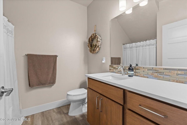 bathroom with toilet, wood finished floors, vanity, baseboards, and tasteful backsplash