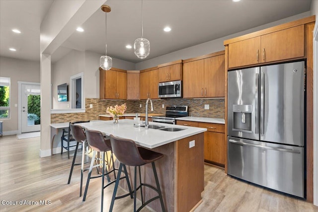 kitchen with stainless steel appliances, brown cabinetry, a sink, and decorative backsplash