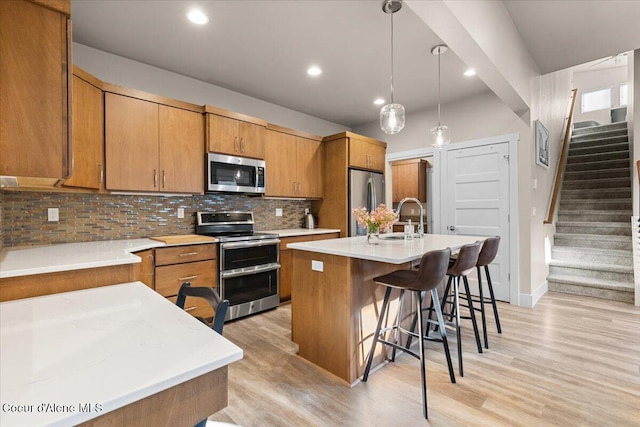 kitchen featuring light wood finished floors, tasteful backsplash, a breakfast bar area, stainless steel appliances, and a sink