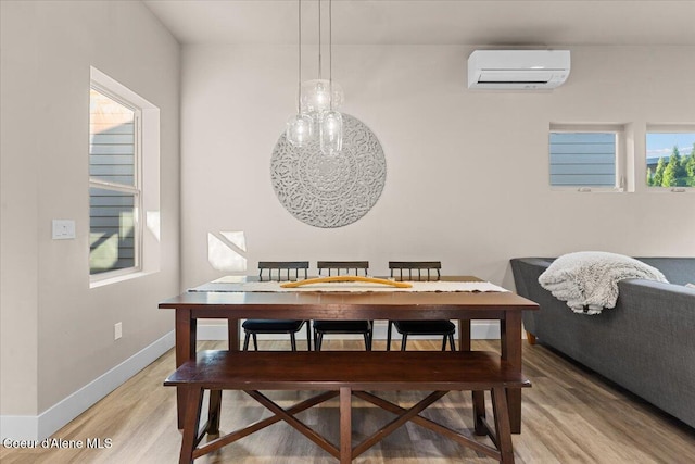 dining room with light wood-type flooring, a wall mounted air conditioner, and baseboards