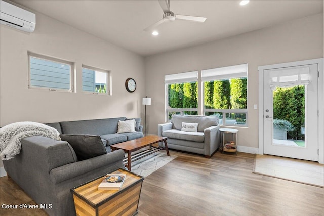 living area with an AC wall unit, wood finished floors, a ceiling fan, and recessed lighting