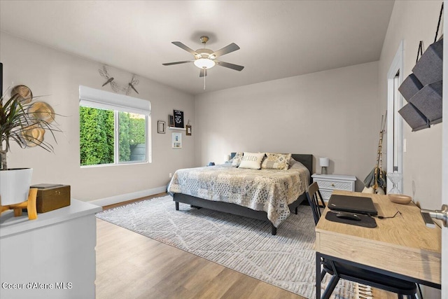 bedroom with a ceiling fan, baseboards, and wood finished floors