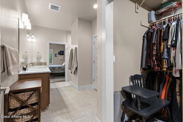 ensuite bathroom featuring visible vents, ensuite bathroom, tile patterned flooring, a walk in closet, and vanity