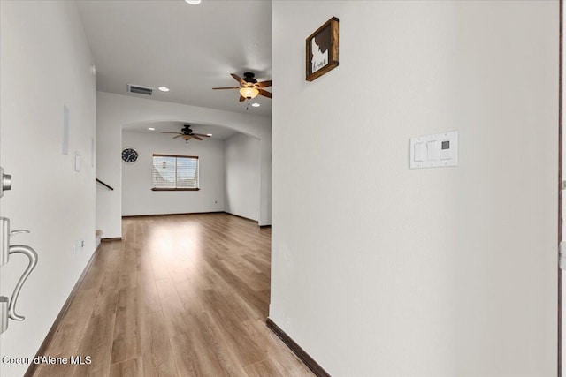 hallway featuring visible vents, wood finished floors, recessed lighting, arched walkways, and baseboards