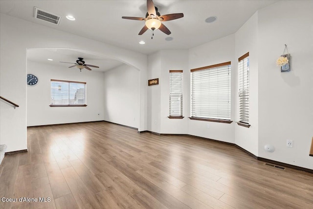 unfurnished living room featuring visible vents, arched walkways, and wood finished floors