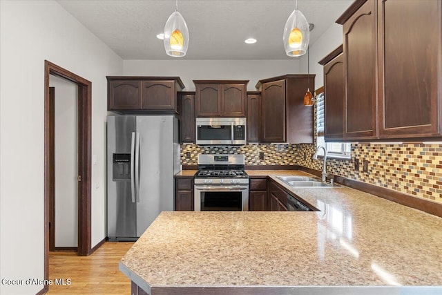 kitchen with a sink, dark brown cabinetry, appliances with stainless steel finishes, light wood finished floors, and light countertops