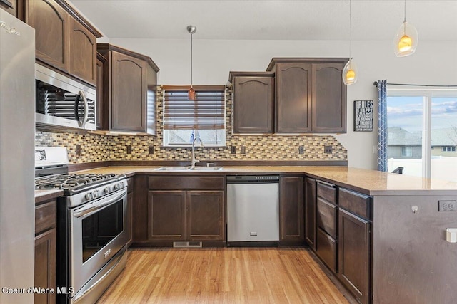 kitchen featuring visible vents, light wood-type flooring, a peninsula, stainless steel appliances, and a sink