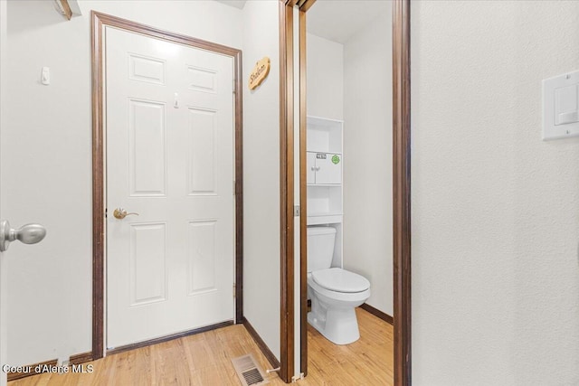 bathroom with visible vents, toilet, baseboards, and wood finished floors