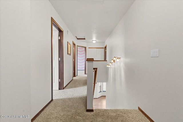 hallway featuring baseboards, an upstairs landing, and carpet floors