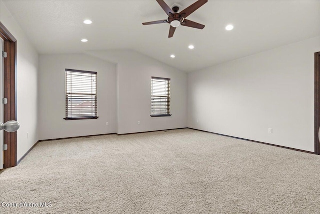 spare room with baseboards, lofted ceiling, a healthy amount of sunlight, and light carpet