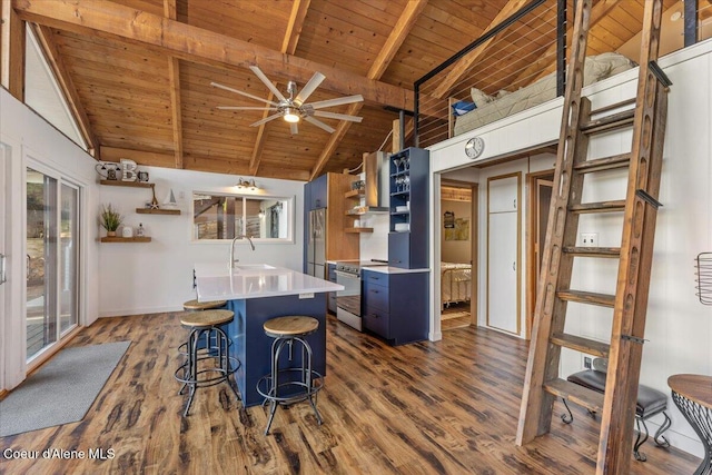 kitchen with a sink, appliances with stainless steel finishes, wall chimney exhaust hood, open shelves, and dark wood finished floors