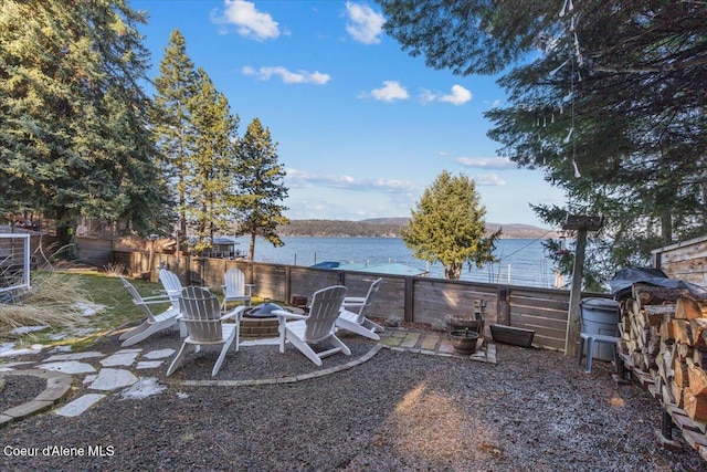 view of yard with a water view, fence, and a fire pit