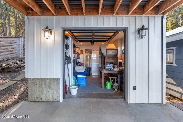 entrance to property featuring a garage, board and batten siding, and electric water heater