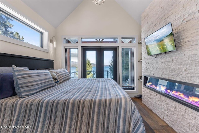 bedroom with french doors, dark wood-style flooring, access to outside, a stone fireplace, and high vaulted ceiling