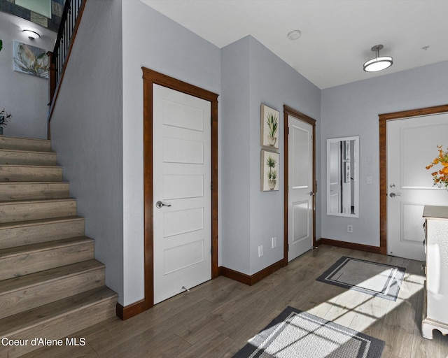 entryway featuring dark wood-type flooring, stairway, and baseboards