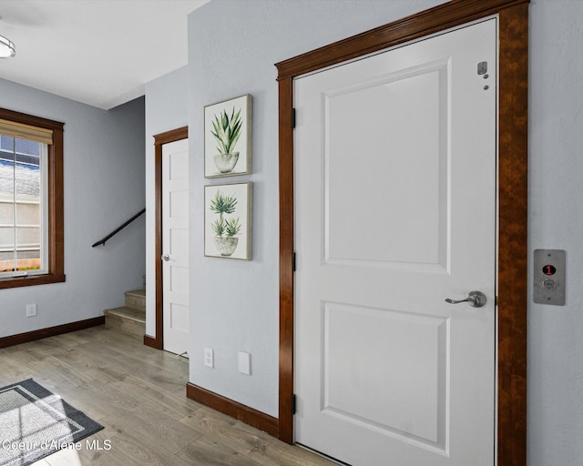 foyer entrance with stairway, light wood-style flooring, and baseboards