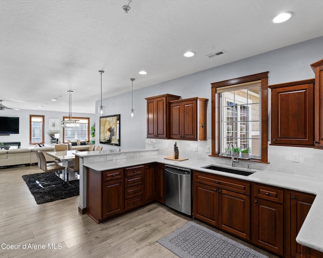 kitchen featuring backsplash, open floor plan, a sink, dishwasher, and a peninsula