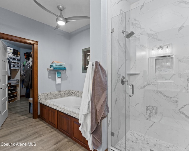 bathroom with a marble finish shower, a ceiling fan, a walk in closet, and wood finished floors