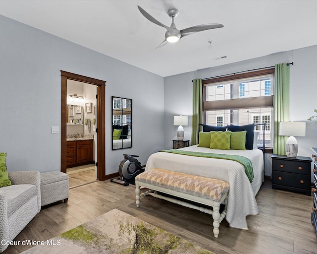 bedroom featuring ensuite bathroom, ceiling fan, a sink, visible vents, and light wood-type flooring