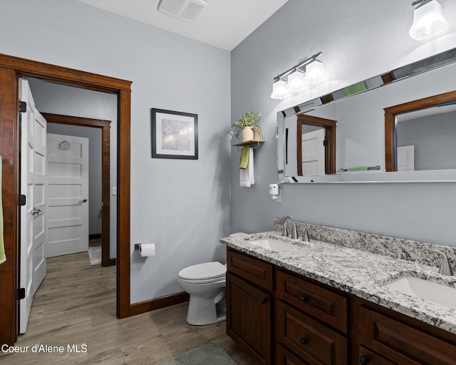 bathroom with toilet, wood finished floors, a sink, and visible vents