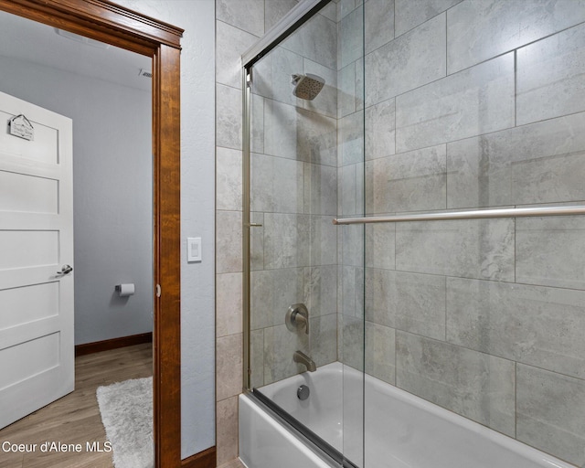 bathroom featuring combined bath / shower with glass door, wood finished floors, and baseboards