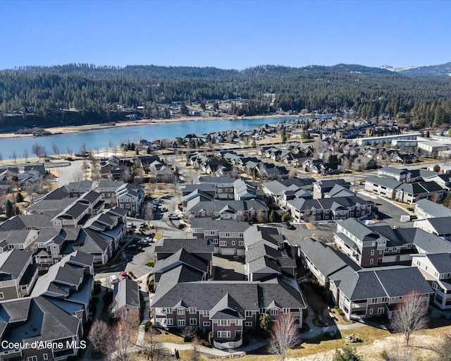 drone / aerial view with a water view, a residential view, and a view of trees