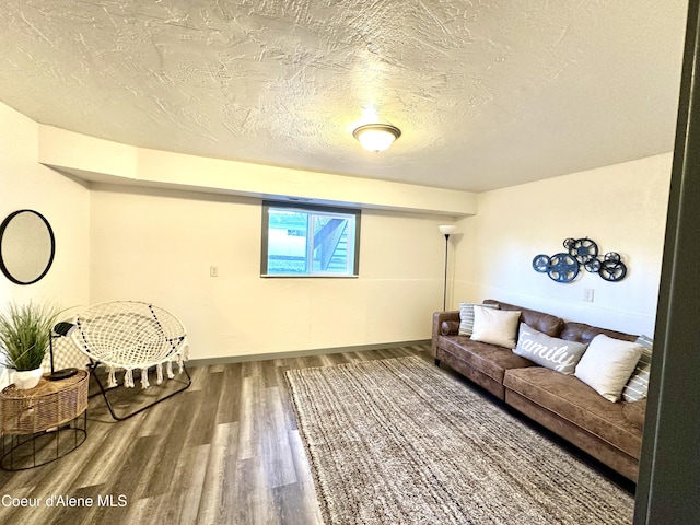 living area featuring a textured ceiling, baseboards, and wood finished floors