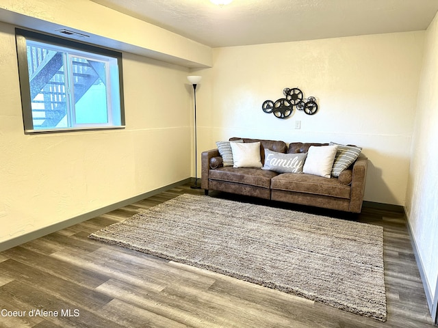 living room with baseboards, wood finished floors, and a textured wall